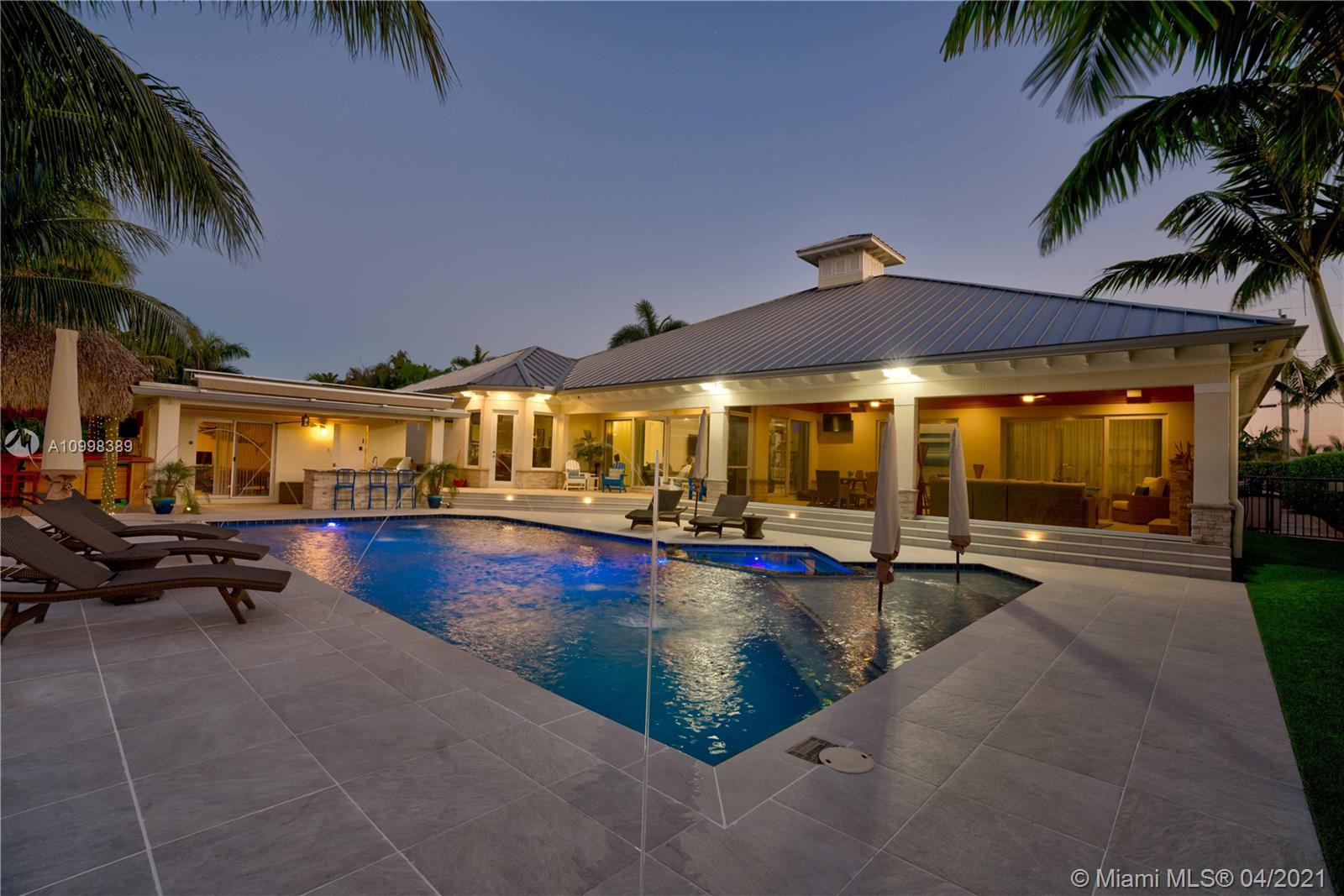 Rarely available! Stunning single story CBS modern estate home on 100’ of waterfront. One of the best "NO HOA" streets in PBG, with wide, deep water canal. No fixed bridges and easy ocean access via Jupiter and Lake Worth inlets. This newer premier estate home has 5 bedroom, 5.1 bath plus office, 3 car garage, impact glass and all the amenities of the South Florida waterfront lifestyle.
Plenty of parking in this brick pavered, horse shoe driveway. Walk through this Mahogany door into a spectacular foyer with wood tray ceiling and salt water fish tank. Open floor plan boosts kitchen with large island, living room and den. Master bedroom plus 3 additional en suite bedrooms plus office in the main house and separate 1/1 guest house. One room currently being used as a media room.
