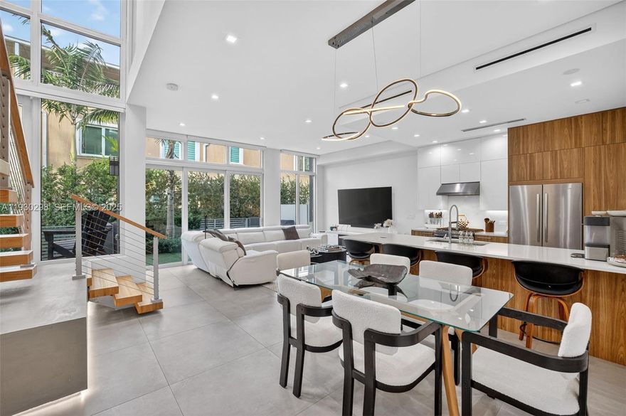 Impeccably maintained modern townhome located in a boutique, eight-unit Victoria Park community. Enter through a dramatic glass-front entry spans two stories, creating a bright, airy atmosphere and effortless indoor-outdoor flow. The open-concept layout is enhanced by soaring 10+ foot ceilings and abundant natural light. A statement floating staircase with stainless accents anchors the main living space. The designer kitchen is outfitted with JennAir stainless appliances, gas cooking, Dell Anno Cabinetry and quartz counter seating. The primary suite serves as a private retreat with its own balcony, walk-in closet, dual vanities, and a spacious glass-enclosed shower and tub. A second-floor loft offers flexible use as a media room or office separating the Primary from the additional two bedrooms. Move right in as this unit comes with custom built out closets, motorized shades, smart home features throughout, and a tankless gas water heater for your convenience. Unbeatable walk-to location near Fort Lauderdale’s newest dining, fitness, shopping, and everyday conveniences. Right around the corner from Holiday Park and the Florida Panthers Practice Facility! Sqft. from Developer is believed accurate.