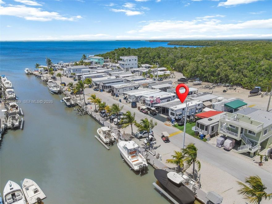 Located in the Calusa community in Key Largo, this is one of the more spacious lots in the neighborhood. Many owners are removing their RVs and building on these lots. The community is known for its unique tree canopy entrance in which every neighbor welcomes you like family. The property includes a new 2025 Sandpiper Destination RV, a large carport with an expansive terrace, and a shed with A/C perfect for storage, hobbies, additional workspace, or an extra weekend guest. It also features its own dock space with a boat lift, making it ideal for boating enthusiasts.