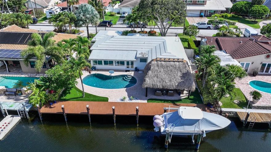Situated on 75' ft of waterfront with deep water access and no fixed bridges! NO HOA. This stunning home in the desirable Pompano Isles community is truly a boater’s dream offering direct ocean access just minutes to the Intracoastal. The sun filled interior features an open floor plan with porcelain tile flooring throughout. The modern white kitchen boasts quartzite countertops, top-of-the-line appliances, and a gas range and oven. Enjoy peace of mind with impact windows & doors, updated plumbing & electric, and a beautifully resurfaced pool. The spacious primary suite offers serene pool views and a spa like ensuite bath with oversized dual shower and double sinks. Step outside to your private waterfront oasis featuring a newer resin dock, boat lift, tiki hut and a small golf putting green, perfect for relaxing or entertaining.