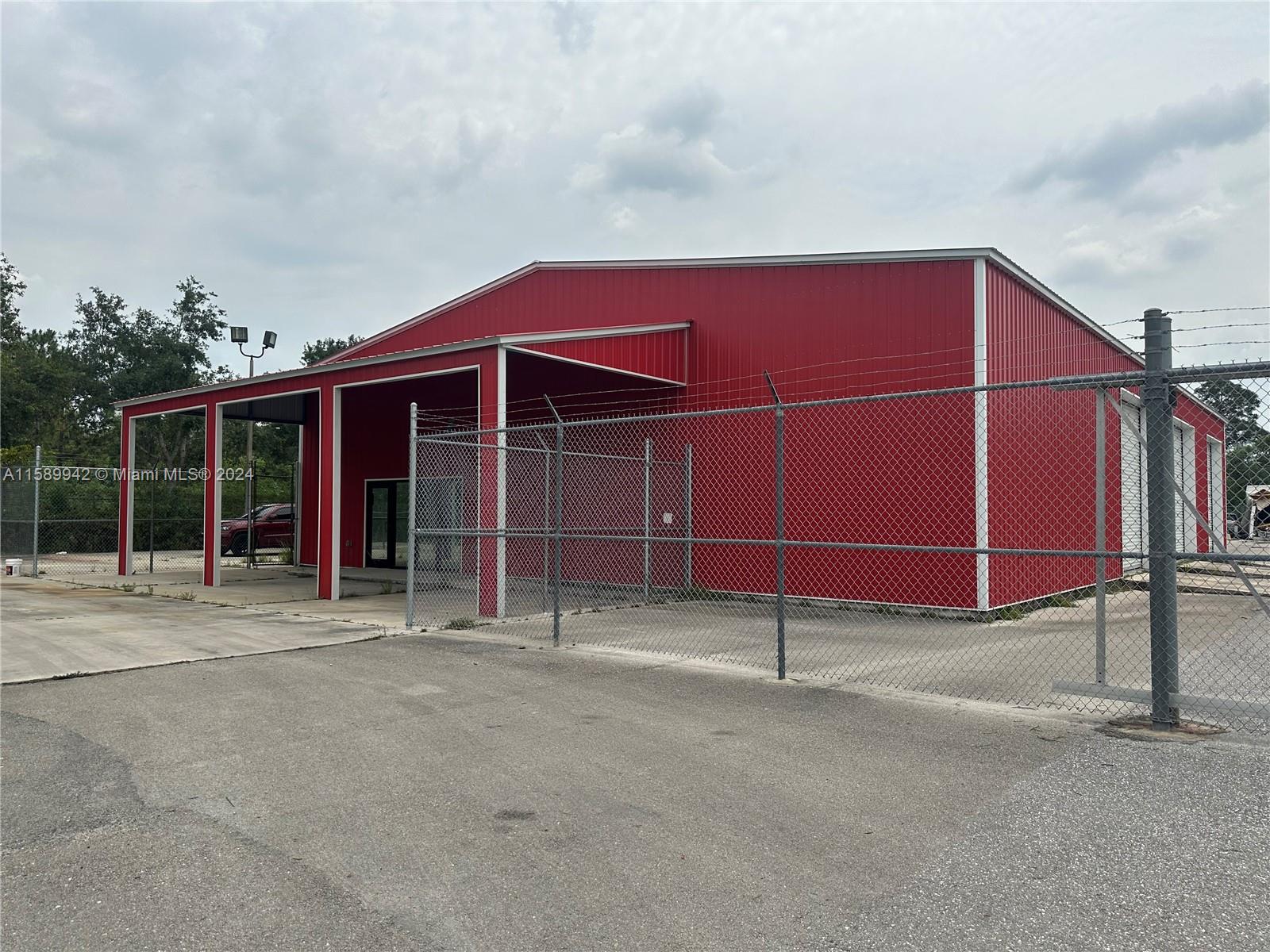 The primary building, designated for storage, is in a condition that resembles new. It contains seven garage bays; six are roughly 14x14 feet. The larger bay, situated at the back, is about 16x16 feet. The interior is equipped with several standard electrical outlets. There is a small office space that has not been utilized. A chain-link fence encloses the property, which is split into two sections, and includes a sizable automated gate.