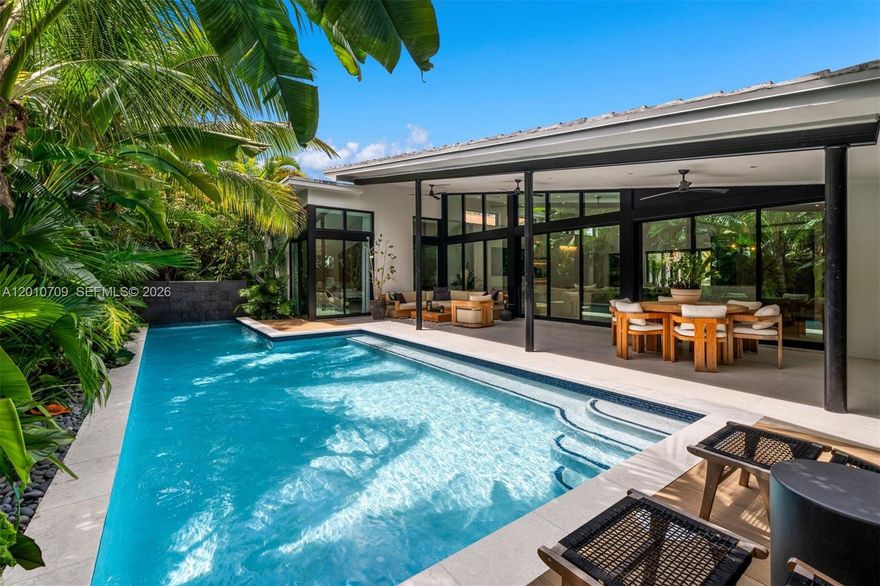 Welcome to a private, gated Mid-Century Modern residence completed in 2021, designed with a focus on both style and comfort. Offered fully furnished, the home features an open-concept living, dining, and kitchen layout with custom built-ins, all connected by floor-to-ceiling glass doors that open to a secluded "Tulum Vibe" backyard with a saltwater pool, waterfall, and tropical landscaping. A covered patio offers space for outdoor dining, along with a front patio and a large driveway. The home includes 4 bedrooms and 3 bathrooms, with porcelain flooring throughout. The kitchen is outfitted with leathered granite countertops, a terrazzo marble island, premium appliances, and a wine fridge. The primary suite features dual vanities, a spacious shower, and an expansive walk-in closet. Filled with natural light and completely turnkey, this is a private, well-designed home ready to enjoy.