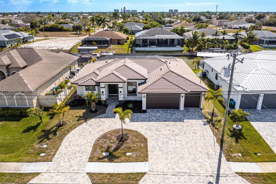 Welcome to a stunning new construction home in the heart of Southwest Cape Coral, just minutes from Cape Harbor, Tarpon Point, waterfront dining, boutique shopping, and all the amenities that make this one of Southwest Florida’s most desirable boating communities. A circular driveway and spacious three-car garage set the tone, leading to a light-filled foyer that opens into an expansive family room with pocket sliders for seamless indoor-outdoor living. The open floor plan is ideal for everyday comfort and entertaining, anchored by a showpiece kitchen with a massive island, custom shelving, and sleek finishes flowing effortlessly into the dining and living areas. The primary suite is a private retreat with sliders to the pool area, custom lighting, generous closets, and a spa-inspired bath featuring a soaking tub and oversized walk-in shower. Guest bedrooms are generously sized, with one offering easy access to the pool bath. Outside, a custom pool and spa overlook a wide canal, complemented by an expansive lanai and outdoor kitchen perfect for entertaining. With Gulf access just minutes away, room for a custom dock or tiki hut, hurricane-impact windows and doors, tile throughout, and luxury finishes throughout, this home combines thoughtful design with the ultimate Southwest Florida lifestyle.