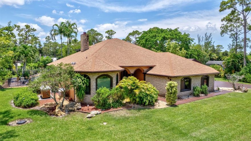 Enjoy luxury, privacy, and peace of mind in this custom-built 2007 estate home, nestled on a privately paved street & sitting on a fully fenced 1.15-acre lot: 4 bdrms, 4 bths, plus office/den. Features newer roof installed in 2022, brand-new AC & accordion shutters throughout, whole-house; brand new water filtration for the whole house, impact windows/doors. Convenient generator with 1,000-gal propane tank and 3-car garage (30’x33’). Enjoy a saltwater pool, 5-person spa, waterfall, and outdoor kitchen. Property has a powered boathouse, a long driveway & a fully equipped gas-powered summer kitchen, perfect for outdoor entertaining. Stone accents, fireplace & tranquil waterfalls in front & back create a peaceful, luxurious setting. Pool table & furniture is a bonus in the 2nd floor- Rec room