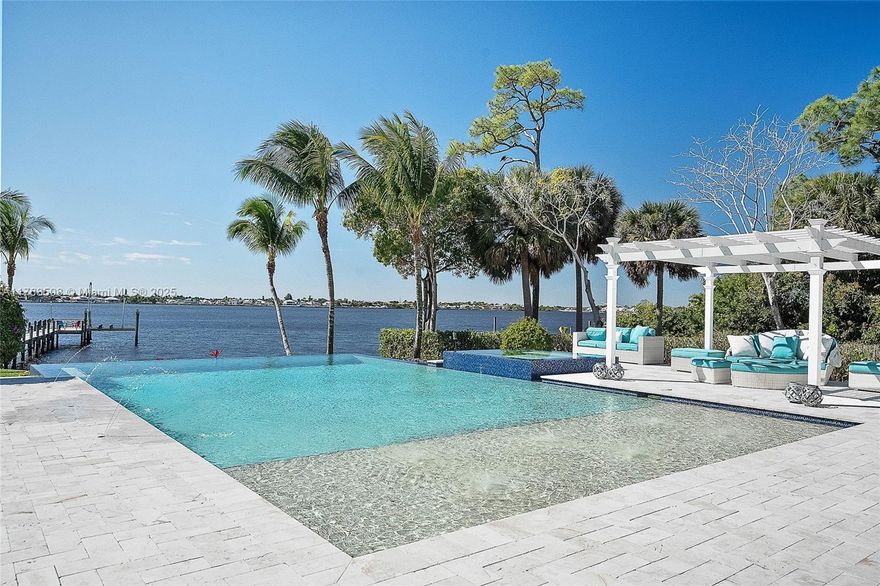 Accepting all offers. Enjoy waterfront living in this 2017 custom estate, now offered at a new reduced price. Privately set behind gates on nearly an acre, the residence was designed to capture sweeping views of the St. Lucie River while blending comfort, elegance, and sophistication.Inside, you'll find six spacious bedrooms, two private offices, 4.5 baths, a 4.5-car garage, & a versatile guest or in-law suite. Soaring ceilings, a sleek metal roof, and seamless indoor-outdoor flow showcase Florida's signature style.Enjoy resort-level living with a spectacular infinity-edge saltwater pool, spa, sun shelf, fully equipped summer kitchen, generator, and your own private sandy beach. Nearly 115 feet of pristine waterfront with a deep-water dock and 20,000-pound lift accommodates...