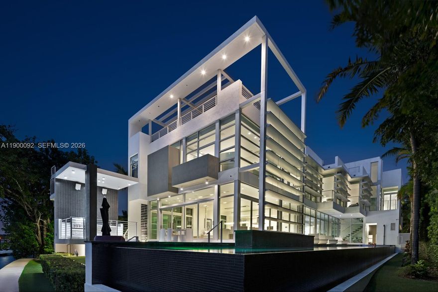 This sleek ultra-modern tri-level waterfront masterpiece is perfectly situated on the coveted tip of Hibiscus Island, offering breathtaking, unobstructed views of the bay, yachts, and the Miami skyline. Designed by renowned architect Roney Mateu of Mateu Architecture, the home features porcelain and oak wood floors, open living spaces, a gourmet kitchen with top appliances, a custom bar, movie theatre with leather recliners, gym, and outdoor kitchen. All bedrooms offer water-view balconies. Outdoor amenities include a heated infinity-edge pool, Jacuzzi with fire pit, summer kitchen, cabana bath, private dock with boat lift, and 85 feet of waterfront. A rooftop entertainment lounge delivers 360° panoramic views, making this residence the ultimate Miami lifestyle experience.