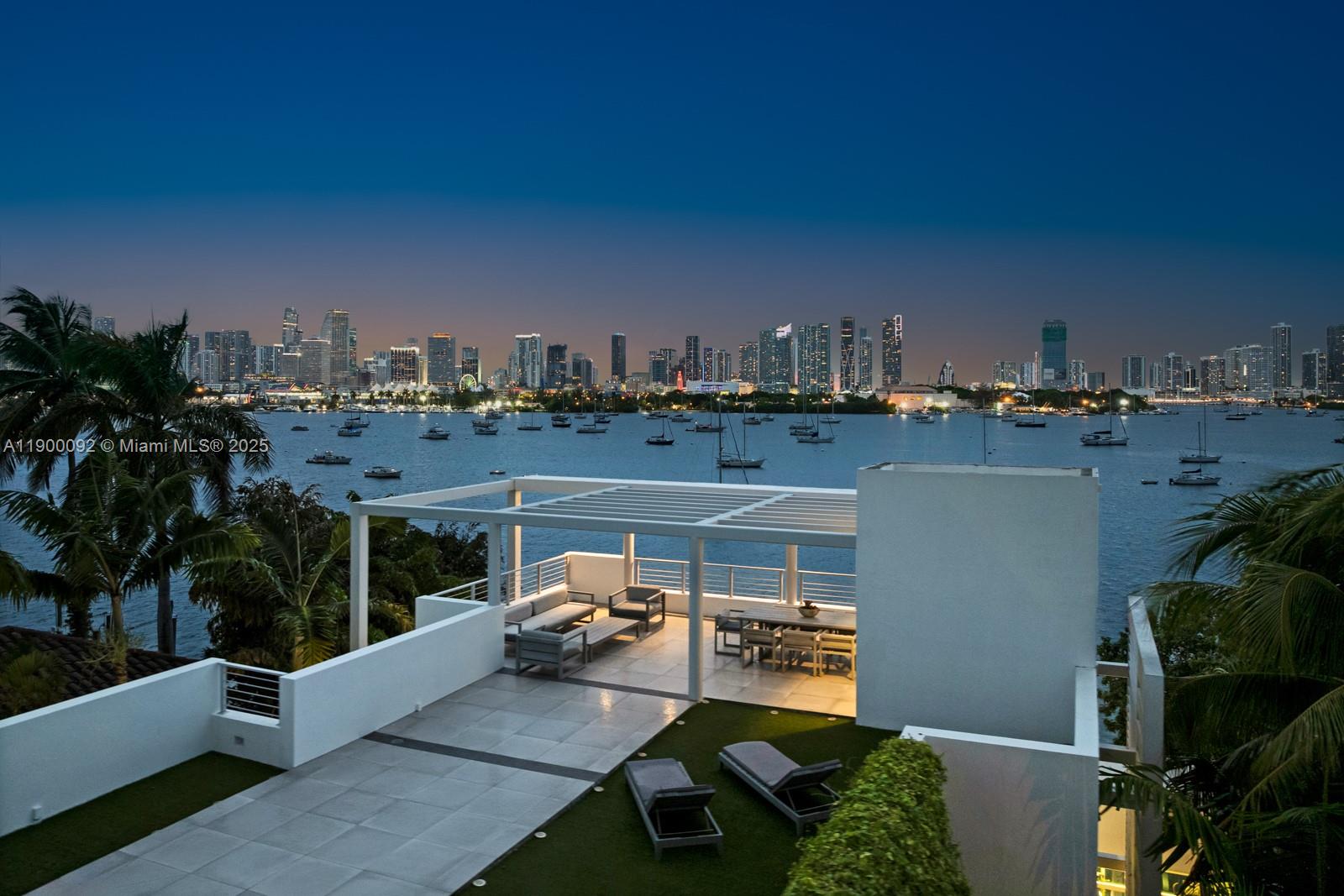 This sleek ultra-modern tri-level waterfront masterpiece is perfectly situated on the coveted tip of Hibiscus Island, offering breathtaking, unobstructed views of the bay, yachts, and the Miami skyline. Designed by renowned architect Roney Mateu of Mateu Architecture, the home features porcelain and oak wood floors, open living spaces, a gourmet kitchen with top appliances, a custom bar, movie theatre with leather recliners, gym, and outdoor kitchen. All bedrooms offer water-view balconies. Outdoor amenities include a heated infinity-edge pool, Jacuzzi with fire pit, summer kitchen, cabana bath, private dock with boat lift, and 85 feet of waterfront. A rooftop entertainment lounge delivers 360° panoramic views, making this residence the ultimate Miami lifestyle experience.