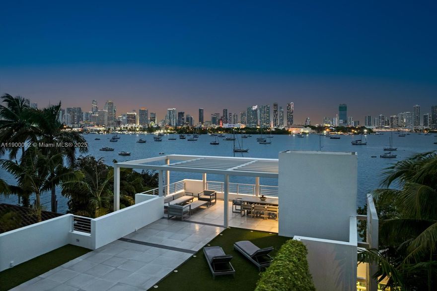 This sleek ultra-modern tri-level waterfront masterpiece is perfectly situated on the coveted tip of Hibiscus Island, offering breathtaking, unobstructed views of the bay, yachts, and the Miami skyline. Designed by renowned architect Roney Mateu of Mateu Architecture, the home features porcelain and oak wood floors, open living spaces, a gourmet kitchen with top appliances, a custom bar, movie theatre with leather recliners, gym, and outdoor kitchen. All bedrooms offer water-view balconies. Outdoor amenities include a heated infinity-edge pool, Jacuzzi with fire pit, summer kitchen, cabana bath, private dock with boat lift, and 85 feet of waterfront. A rooftop entertainment lounge delivers 360° panoramic views, making this residence the ultimate Miami lifestyle experience.