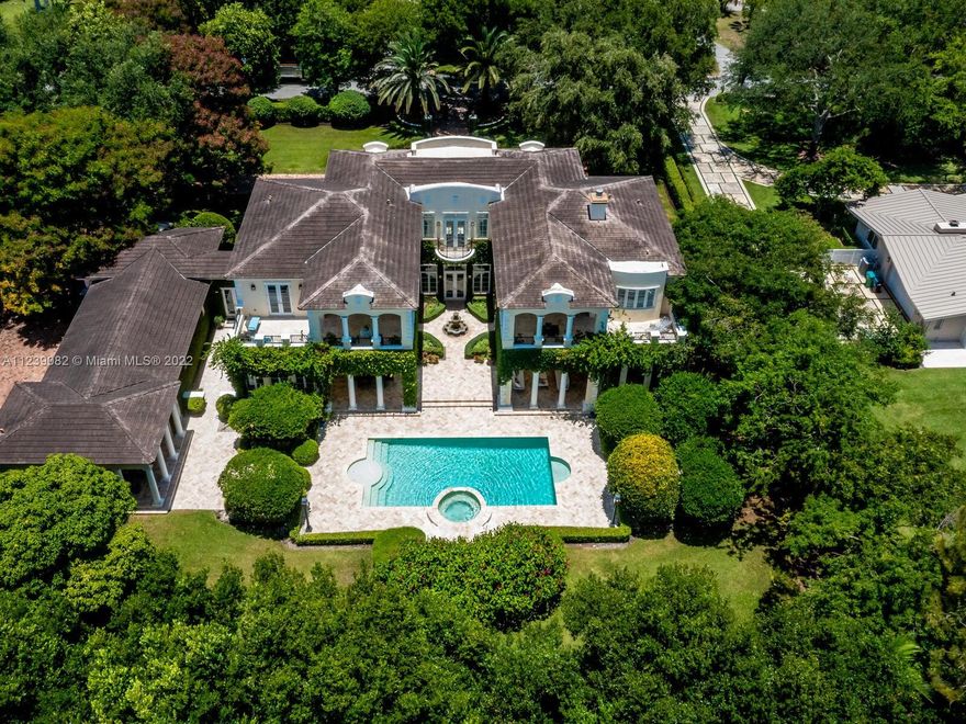 French Neoclassical Pinecrest Estate. Nestled in total privacy amid lush pristine landscaping, this sprawling residence is an extravaganza of indoor/outdoor architectural artistry. Vast marble terraces & covered columned balconies surround it. A stunning ivy-covered courtyard w/fountain divides the wings, fronting the designer pool & spa. An immense foyer introduces the grandeur w/2-stry ceiling, sky-hi windows, candelabra chandelier, creamy marble flrs & winding statement staircase w/wrought-iron rail & marble steps. Every room is brightened by banks of windows + recessed & artistic lighting. Entertain in formal + casual dining rms & living + family rms. The giant, dual-island kitchen is a chef’s dream! Wood flrs in bdrms. Roman tub in master bath. Room-size master closet. Generator, 3CG.