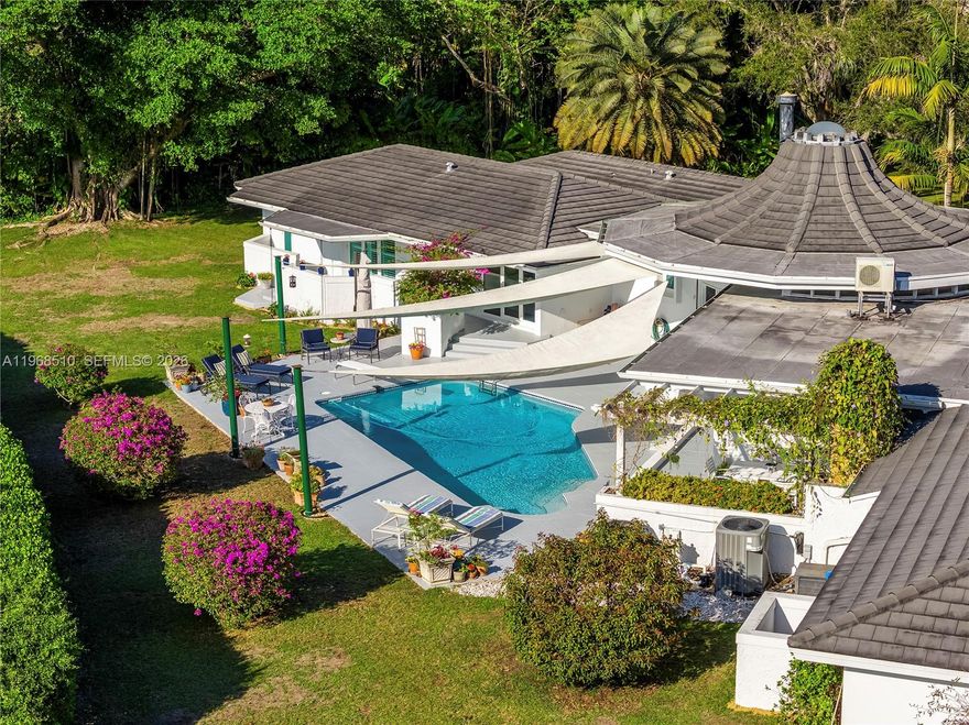 Set on a premier builder’s acre in the heart of Pinecrest, Florida, this striking canal-front estate is a rare blend of architectural pedigree, thoughtful updates, and timeless design. Originally conceived by noted architect Barry Sugerman, the home makes an unforgettable first impression with its dramatic wood rotunda entry, soaring ceilings, and signature curved walls that create a sense of flow and quiet sophistication throughout. Spanning over 5,000 square feet, the residence offers five bedrooms and five baths, including private staff quarters. The interiors have been beautifully refreshed, featuring rich cherry hardwood floors, marble finishes, and custom Italian doors. The chef’s kitchen is both functional and stunning, equipped with double Wolf gas ovens, an oversized Sub-Zero refrigerator, and a generous workspace designed for both everyday living and entertaining. Walls of impact glass open to a resort-style outdoor setting with a sparkling pool, expansive grounds, and tranquil canal views, enhancing the home’s sense of privacy and scale. A three-car garage, newer roof, and location within Pinecrest’s top-rated school district further elevate the offering. This is a home for those who appreciate architecture, space, and one of Pinecrest’s most desirable waterfront settings. An exceptional opportunity to own a truly distinctive property.