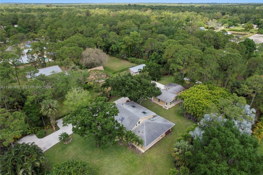 Rare, custom concrete, 2 building estate on paved roads in Jupiter Farms. This 2014-rebuilt, full CBS concrete-filled, steel-reinforced home offers unmatched durability with spray foam insulation and hurricane-impact windows. Situated on a high-elevation, gated, fully fenced lot with no HOA, with ample space for RVs, boats, and equipment. The main home features soaring ceilings, oversized skylights, and a chef’s kitchen with thick marble counters. Enjoy a primary spa-suite with a two-person granite shower. Outdoor highlights include a covered grill patio and a rare, maintenance-free 8-person built-in stainless hot tub. Detached 450 sq ft guest house (rebuilt 2023) features a private sauna. Includes 400-amp service, two gated driveways, and a 30 ft storage shed. Concrete filled, steel reinforced walls, spray foam insulation, a ceramic coated exterior, and full hurricane impact windows and skylights, storm ready structure.