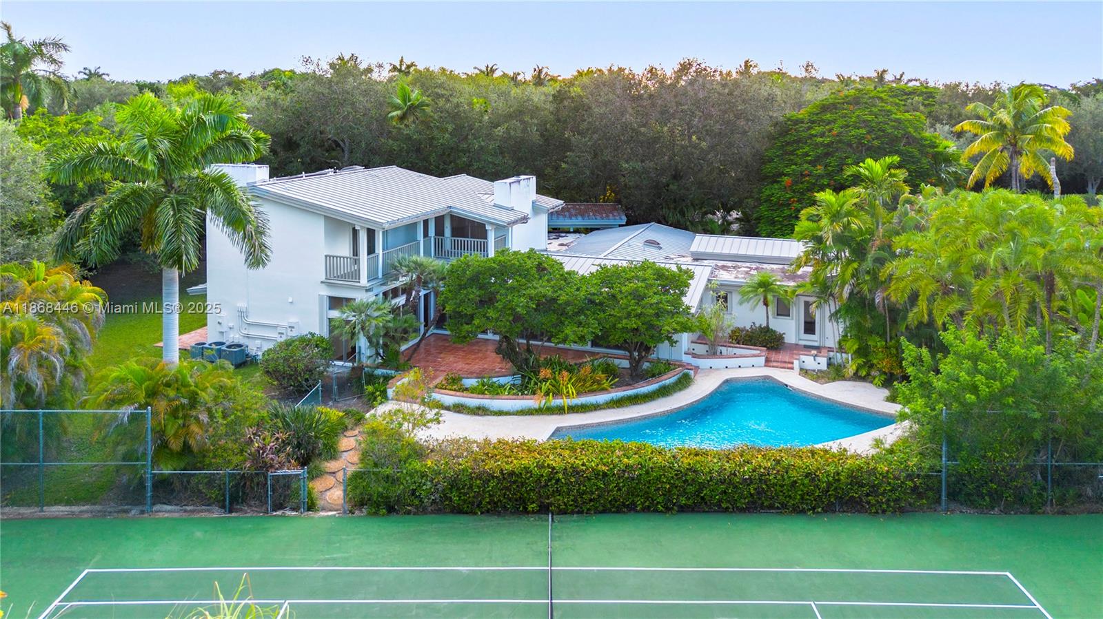 Spacious Mid Century Pinecrest Estate with HIGH CEILINGS on a 39,204 SF Lot with a Tennis Court in desirable SE Pinecrest! This 6 bed, 5 bath Pinecrest gem offers 4,405 SF with timeless charm. The upstairs primary suite overlooks the spacious backyard, while 5 additional bedrooms are conveniently located downstairs. From every window, enjoy lush greenery & the privacy of your expansive yard. Soaring ceilings, exposed beams, tongue-and-groove finishes, and coral stone cladding throughout the interior & exterior add rich character. The oversized family room flows into the kitchen and cozy breakfast nook, perfect for gatherings & offering endless potential! Set in an unbeatable location, just steps from the future Aleyda Mas Park & close to top-rated schools. It’s not Miami, it’s Pinecrest!