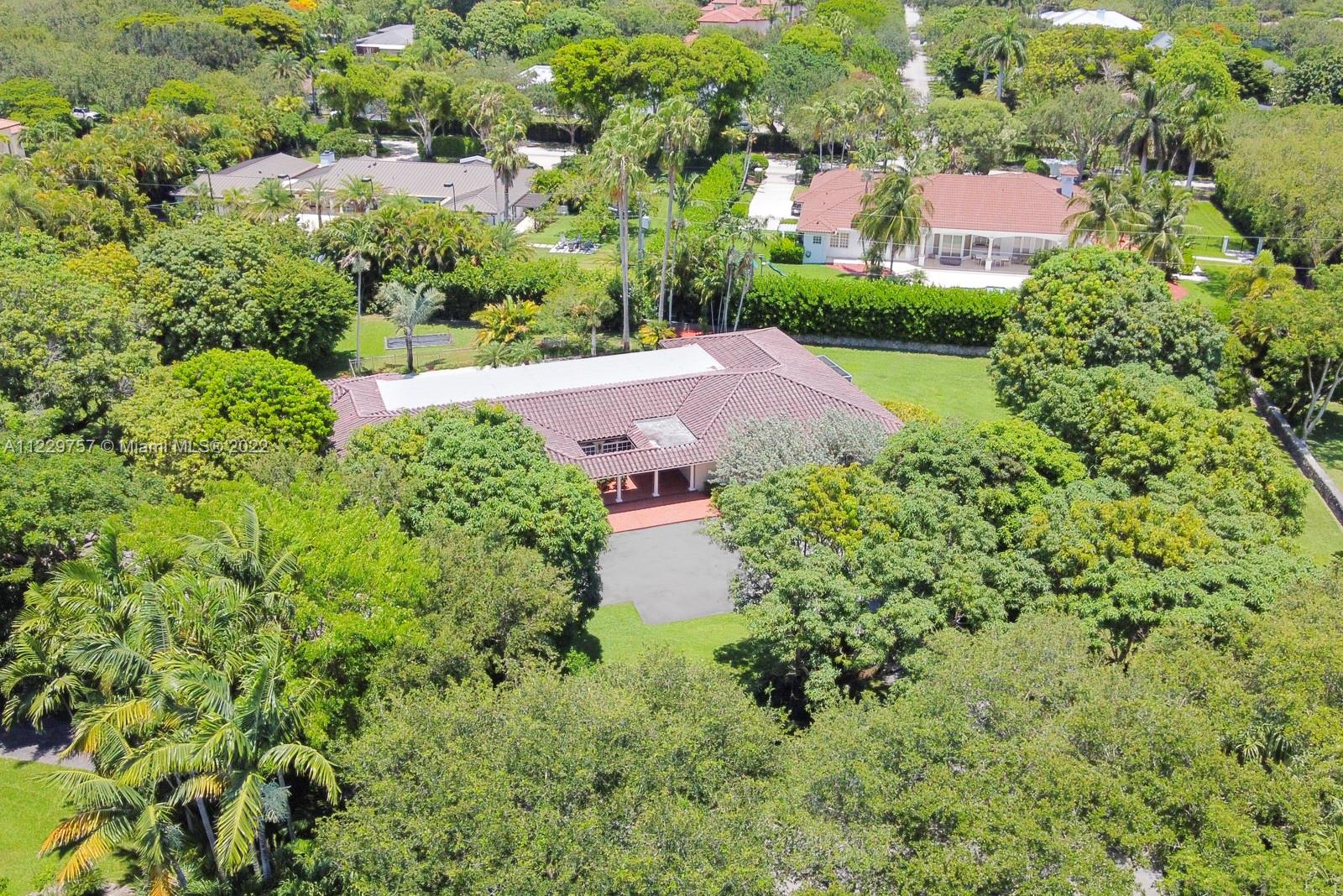 The largest lot (1.15 acre) and most private location within the coveted security patrolled subdivision of Devonwood. Sprawling 5000 adj sq ft. 5 bedroom 4 bath ranch home with large wonderful entertaining and living spaces. Huge family room with vaulted ceiling, large indoor laundry room (which is big enough to carve out a maid's room as well), oversized formal living room and large dining room, copper gutters, barrel tile roof with 2021 flat roof, 2020 4-Ton AC, and 1994 redone marble master bath. One of the largest covered and screened-in patio areas around which is ideal for entertaining. Lush private yard is filled with various mango tree species, lychee trees, avocado trees, and tons of privacy. Exceptionally well maintained property- second time ever on the market!