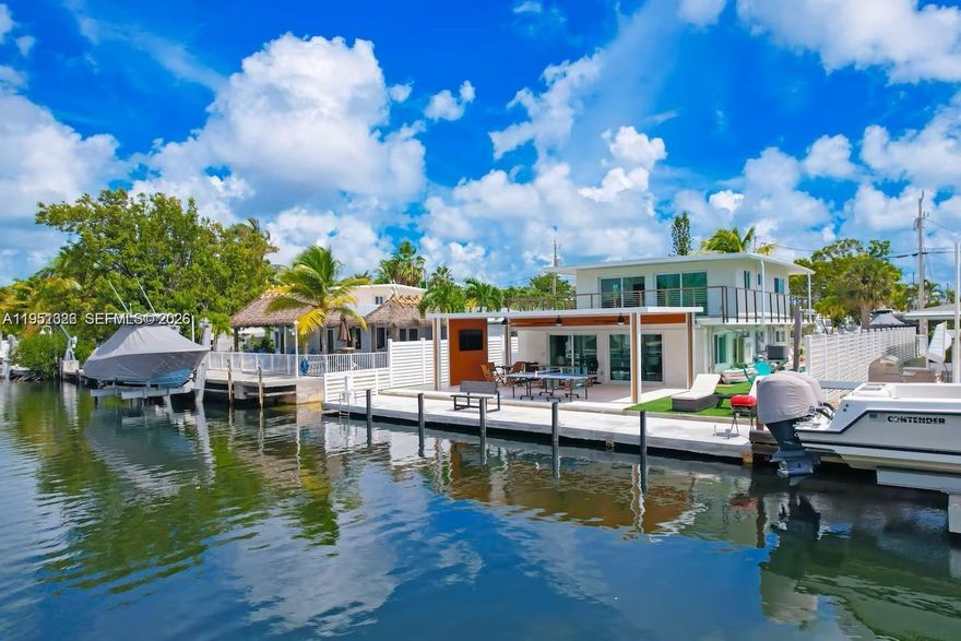 Experience luxury waterfront living in the heart of the Florida Keys! 4 bedrooms and 2 bathrooms. This stunning modern home offers sleek finishes, breathtaking canal views, and direct boating access. Enjoy the spacious outdoor entertainment area, complete with a private dock, lush synthetic turf, and a large jacuzzi—perfect for relaxing under the stars. The upper-level terrace provides an ideal setting for lounging or hosting guests while enjoying the coastal breeze.