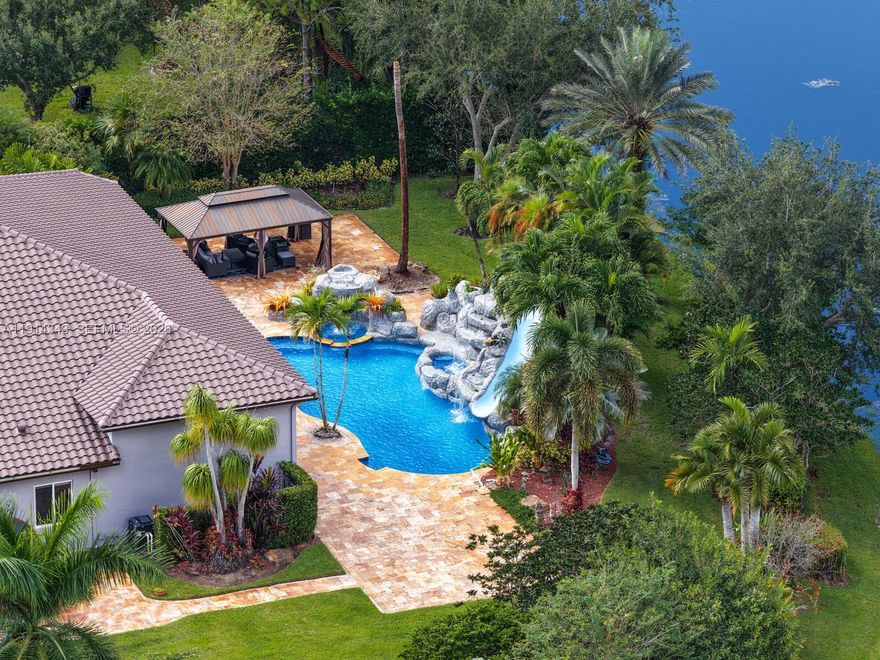 PIICE IMPROVEMENT on one of the community's most exceptional estate properties! 
Perfectly positioned at the end of a private cul-de-sac on the largest lot in the neighborhood, this sprawling residence is surrounded by tranquil canal views, lush tropical landscaping, and expansive outdoor living space designed for the ultimate South Florida lifestyle.
This entertainer's dream features a new roof, fully renovated resort-style pool with resurfacing, new pumps, dual hot tubs, waterslide, and app-controlled lighting. Enjoy a stunning oversized sauna with serene backyard views, a fully equipped summer kitchen, covered outdoor entertainment area, and seamless indoor-outdoor living. 
Inside, the home offers a gourmet kitchen with center island and butlers pantry, step-down full bar, private office, cabana bath, impact windows and doors, full-house generator, and a 1,000-gallon propane tank. A rare opportunity combining privacy, space, luxury, and lifestyle.