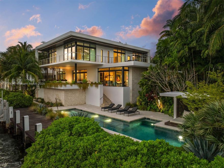 A true Max Strang masterpiece in Coconut Grove’s exclusive Four Way Lodge. This 10,556 SF contemporary waterfront home blends bold architecture with refined natural materials— Italian Basaltina stone, warm wood, Ipe, and Balinese limestone. Enjoy ~150’ of waterfront with a 50’ dock, boat lift, saline lap pool, and Kalamazoo summer kitchen with premium finishes. Floor-to-ceiling Fleetwood impact windows invite natural light, complemented by Kreon lighting, Lutron shades, and Sonos throughout. A BINOVA kitchen with Wolf/SubZero appliances opens to covered terraces. The main house offers 4 BD and 5.5 BA; a separate guest structure includes 2 BD,1.5 BA, and an art studio. An 8+ car garage, EV charger, 1,000 bottle wine chill room, smart home system, and generator complete this rare offering.