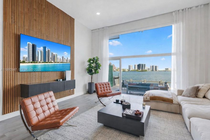 This residence captures the essence of Miami waterfront living. A rare multi-level flat offering a sophisticated yet serene lifestyle with panoramic bay views visible through floor-to-ceiling glass on every level.

Water and skyline become the backdrop to everyday living. The open split-level layout creates a dramatic yet comfortable flow between the living, dining, and kitchen areas, all oriented toward the bay.

The residence features 3 bedrooms, two and a half bathrooms, and a versatile flex room that can serve as a home office, den, or additional guest space. The layout is designed to maximize natural light, openness, and a strong connection to the water.

Outdoor living is equally impressive. A spacious bi-level waterfront deck extends from the living area to a private dock, creating a seamless indoor-outdoor setting ideal for entertaining or relaxing by the bay. The dock accommodates a boat up to 28 feet and offers approximately 30 feet of waterfront with a boat lift.

Additional highlights include a full balcony and a private garage for added convenience and privacy.

Located in the guard-gated community of Eastern Shores with 24/7 patrol by North Miami Beach Police, residents enjoy both tranquility and security, along with direct ocean access via Haulover Inlet with no fixed bridges.