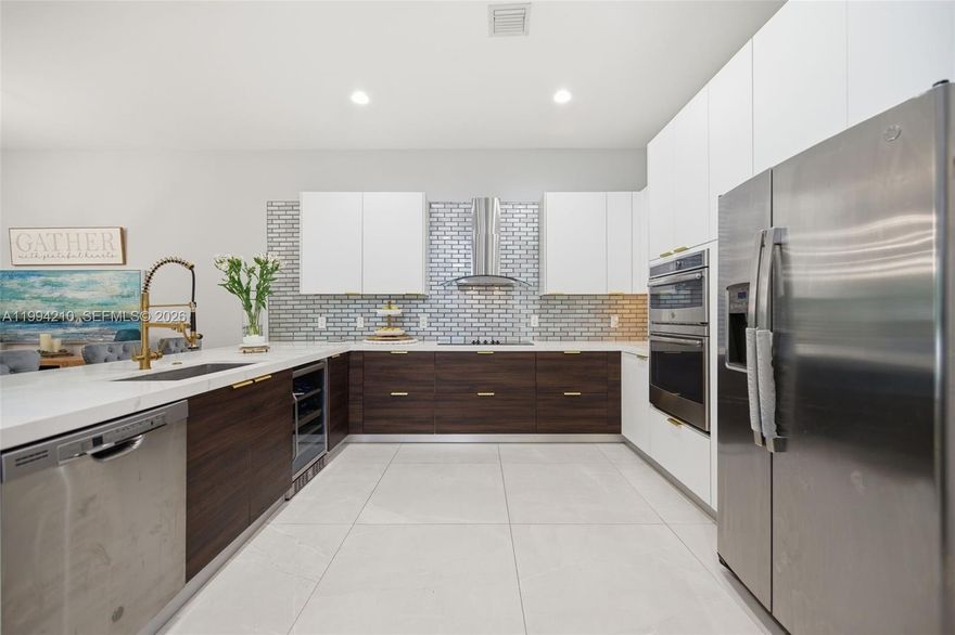 Step into refined South Florida living in this 2020 impeccably designed corner-unit newer construction townhome residence. The open-concept living space is anchored by a show-stopping chef’s kitchen featuring quartz countertops with a dramatic waterfall edge, custom Italian cabinetry, gold hardware, premium stainless steel appliances, and a built-in wine cooler—perfect for entertaining in style. The living area is a true centerpiece, showcasing a striking stacked stone feature wall with a 72” electric fireplace and integrated surround sound, while a designer chandelier defines the dining space. The first level is completed by a stylish powder room and oversized 2-car garage with an epoxy finished floor. Upstairs, the expansive primary suite offers a private retreat with a spacious walk-in closet and spa-inspired bath featuring dual vanities, a soaking tub, and a rainfall shower. Three additional bedrooms, a full bath, and a dedicated laundry room provide plenty of space for everyone.  Ideally located in the heart of Dania Beach, just minutes from Dania Pointe, pristine beaches, fine dining, and major highways including Interstate 95, 595,  and Florida Turnpike—this home delivers the perfect blend of luxury, lifestyle, and location.