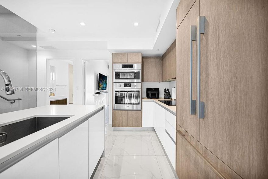 Residence 205 at ONE Bay presents a rare opportunity to own a sun-drenched, turnkey townhome in one of Miami’s most walkable enclaves. Spanning 1,645 SF with a 703 SF private rooftop and 150 SF terrace, this 2-bedroom, 2-bath residence is defined by a striking 22’ south-facing window and a thoughtfully designed split-level layout. Framed by lush tree-lined views, the home has been
meticulously maintained and enhanced with an EV charger and advanced water filtration. Set within a boutique gated community with pool, lounge areas, and guest parking, and offering 2 parking spaces, this pet-friendly residence is moments from the Design
District, Midtown, and Wynwood. Fannie Mae-approved, offering enhanced financing flexibility and broader buyer access.