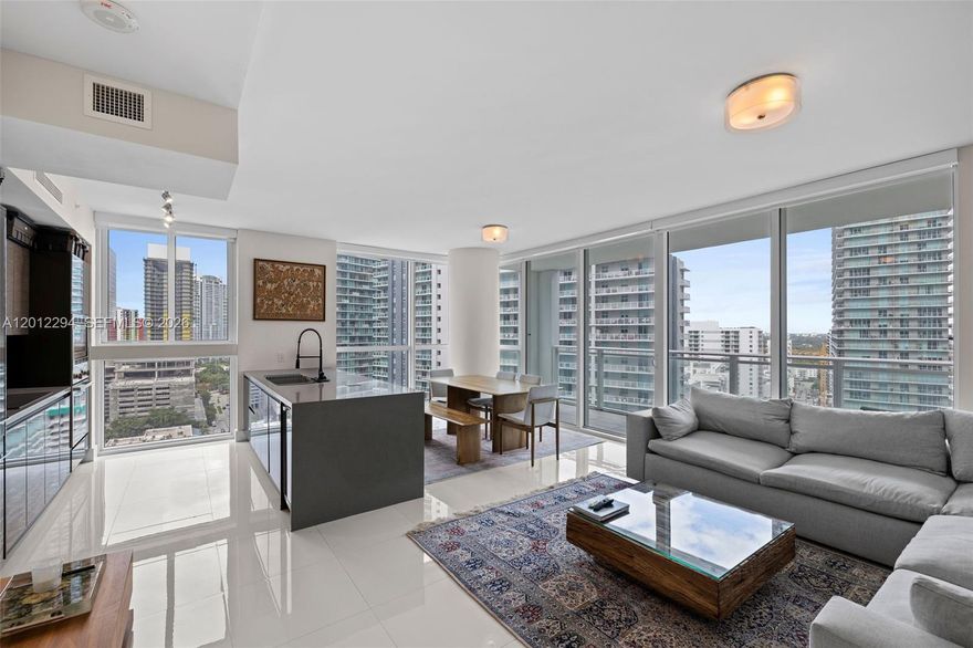 Corner residence at The Bond with floor-to-ceiling glass and open city views. Bright layout with a spacious balcony off the living area. Fully furnished and move-in ready. Modern kitchen with oversized island, Bosch appliances, and sleek cabinetry, opening to a generous living and dining space. Primary suite features a custom walk-in closet and a modern bath with double sinks and glass shower. Second bedroom is well-sized and also works well as a home office. Full-size washer and dryer and excellent storage throughout. One assigned parking space plus valet available. The Bond offers full-service amenities including resort-style pool, fitness center, spa with sauna and jacuzzi, business center, playroom. No pets.