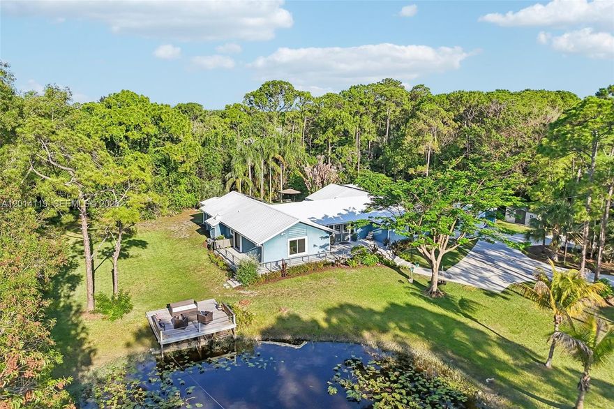 Rarely available Luxury Estate in the heart of Palm Beach Gardens on a fully fenced and manicured 1.15-acre lot! This extensively remodeled pool home blends elegance, privacy, and modern efficiency with a gourmet kitchen featuring granite countertops, custom cabinetry, stainless steel appliances, and a large island. Upgrades include real wood flooring, remodeled baths, impact windows and doors, metal roof, solar power system. Enjoy a resort-style saltwater pool, screened lanai, wraparound concrete deck, stocked pond with dock, tropical landscaping, and versatile "She Shed" that is insulated with split AC, electric, and can be used as an office retreat or man cave —This gorgeous home is offering a unique opportunity for luxury country-style living while remaining close to everything Palm Beach Gardens has to offer!