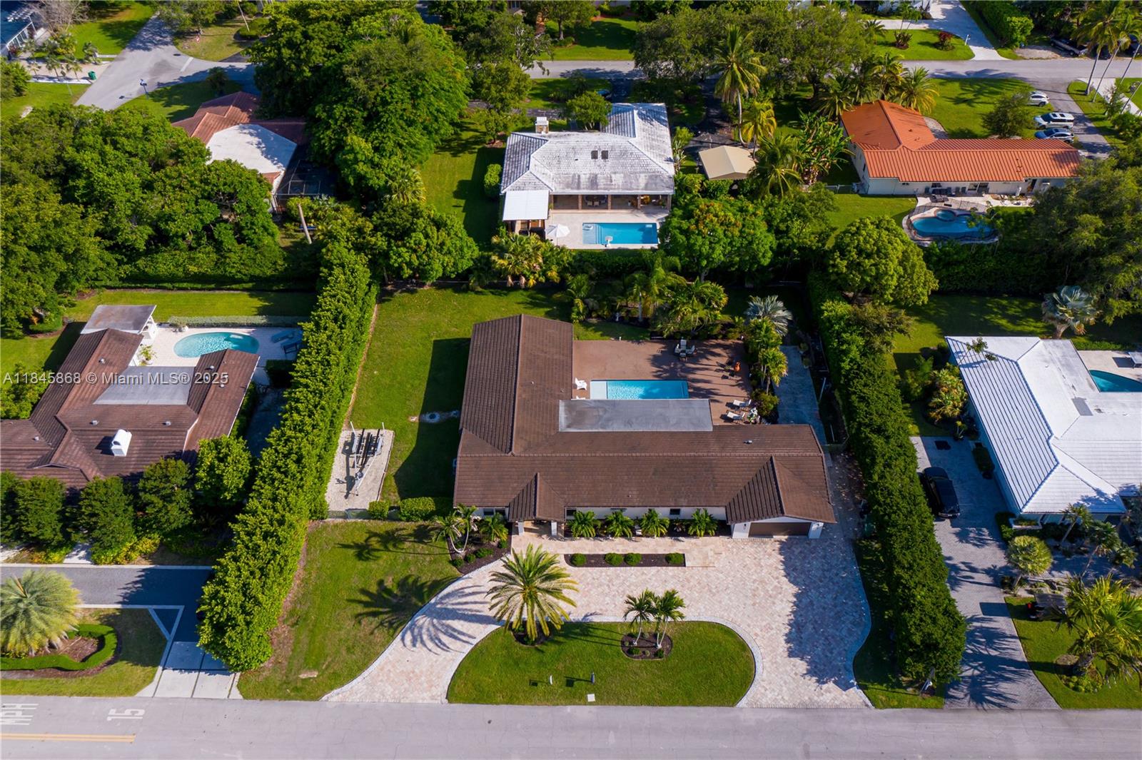 Expanded to 2,885 living sq ft with permits. Impact windows/doors. 2018 concrete roof tile. Exceptional 4/3 Palmetto Bay home designed for comfort, entertaining, and outdoor living. Ideally located near top-rated public/private schools, parks, shops, and bike paths in a quiet residential area. The spacious primary suite features his and hers walk-in closets, an updated in-suite bath with dual showers/sinks, and its own tankless water heater. The large kitchen boasts wood cabinetry, granite countertops, and an L-shaped counter with seating capacity for 4. Open living, dining, and family areas offer easy flow, with French doors throughout connecting indoor and outdoor spaces. Includes oversized 2-car garage, dedicated laundry room with cabinetry and utility sink.