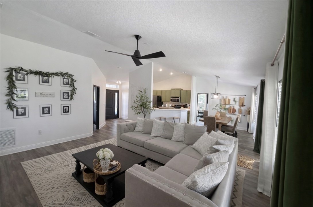 Living area featuring vaulted ceiling, dark wood f