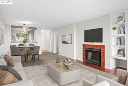 Carpeted living area featuring a brick fireplace and baseboards