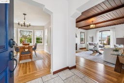 Entrance foyer featuring a chandelier, plenty of natural light, a wooden ceiling with exposed beams, light wood-style floors, and a fireplace with flush hearth