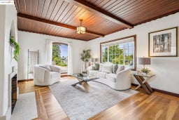 Living room featuring healthy amount of natural light, a wood ceiling with exposed beams, a fireplace, and wood finished floors