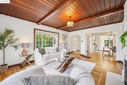 Living area featuring a chandelier, a wood ceiling with exposed beams, and light wood-style floors