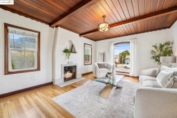Living area with a wood ceiling with exposed beams, a lit fireplace, and light wood-type flooring