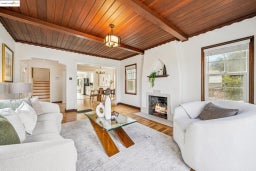 Living area with stairway, a wooden ceiling with exposed beams, a chandelier, light wood finished floors, and a lit fireplace