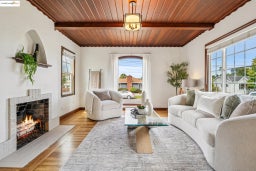 Living room featuring a wood ceiling with exposed beams, a warm lit fireplace, and wood finished floors