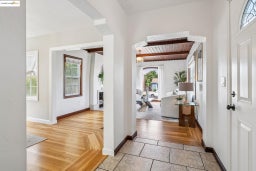 Foyer entrance featuring beamed ceiling, light wood-style floors, and a fireplace
