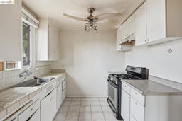 Kitchen featuring white cabinetry, tile countertops, a stainless steel gas range, and a dual basin sink