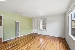 Hardwood flooring featuring an entryway with a panel door, multiple windows with blinds, and a wall heater