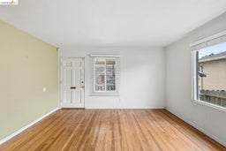 Hardwood flooring throughout the room, complemented by a white six-panel entry door
