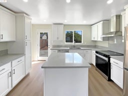 Kitchen featuring appliances with stainless steel finishes, wall chimney exhaust hood, a kitchen island, light wood-type flooring, and recessed lighting