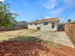Rear view of house with stucco siding, a fenced backyard, and a patio area