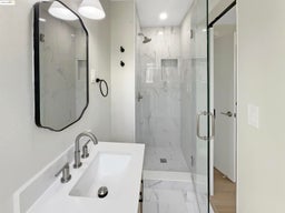Bathroom featuring marble look tiles, a marble finish shower, and vanity