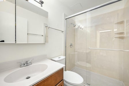 Bathroom featuring a wood-finish vanity with an integrated white sink, a chrome two-handle faucet, and a large medicine cabinet mirror