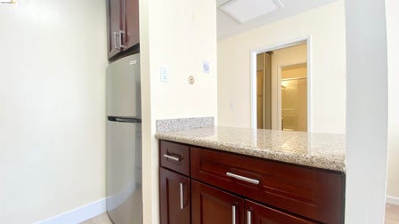 Kitchen area featuring a stainless steel refrigerator, dark wood-finish cabinetry, and a light-toned speckled countertop