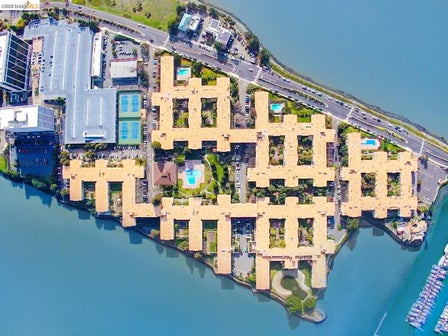 Aerial photography. Residential and commercial structures situated on a landmass bordered by water and a roadway