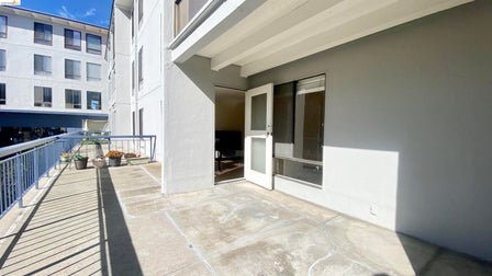 Private outdoor patio featuring a concrete surface, painted stucco exterior, and a white screen door