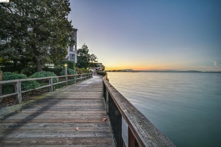 Waterfront boardwalk featuring a wooden railing and integrated path lighting