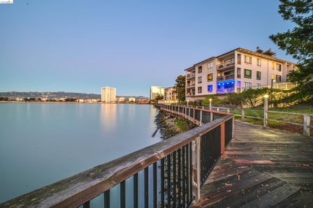 Waterfront multi-story building featuring multiple balconies and a ground-level patio with blue accent lighting