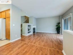 Unfurnished living room with light wood-type flooring, a glass covered fireplace, and stairs