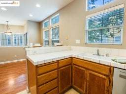 Kitchen featuring tile countertops, brown cabinetry, pendant lighting, a peninsula, and recessed lighting