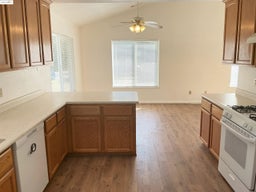 Kitchen with a peninsula, white appliances, a ceiling fan, light countertops, and light wood finished floors